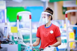 A cashier in medical protective mask and face shield working at supermarket
