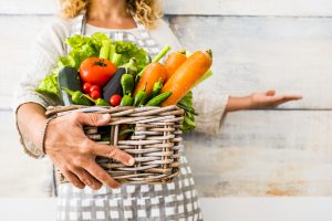 Close up with caucasian woman taking a bucket full of coloured and fresh seasonal vegetables for a healthy and natural food lifestyle - wellness and diet concept lifestyle