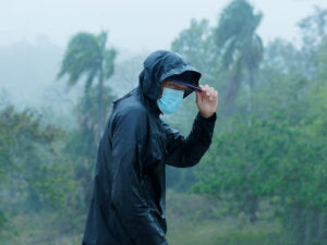 Man wears a face mask in heavy tropical rain