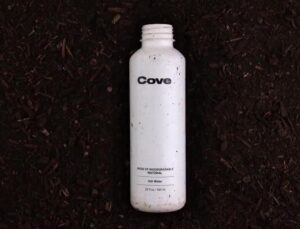 Cove biodegradable bottle laying on soil