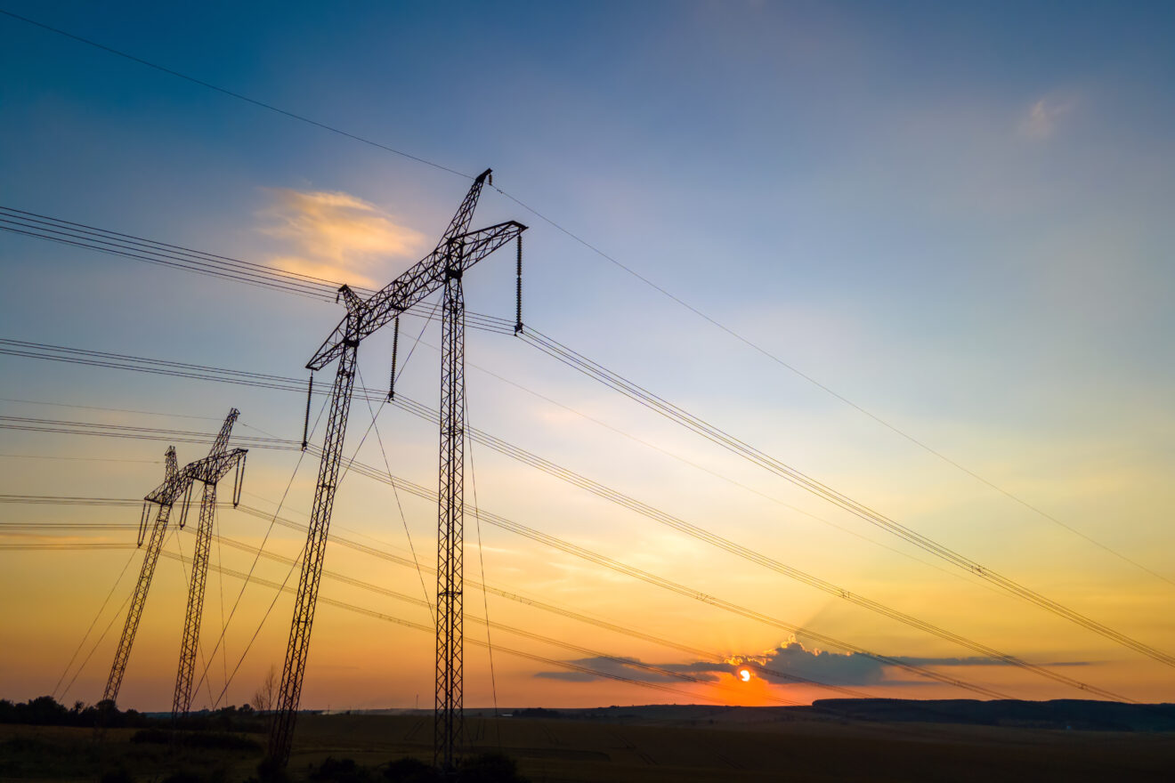 Silhouette of high voltage towers with electric power lines at sunrise