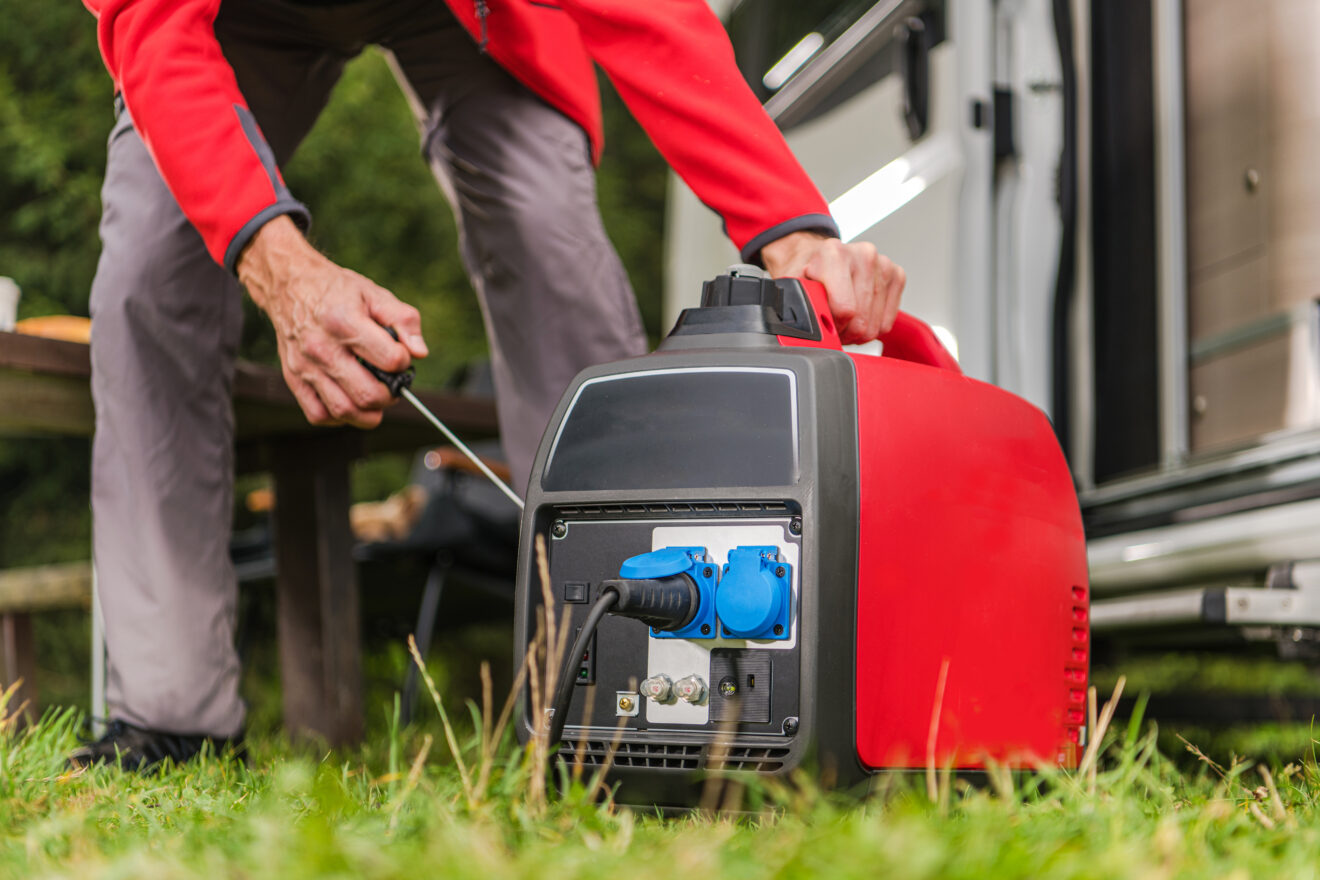 Caucasian Men in His 40s Firing Up Gas Powered Portable Inverter Generator To Connect Electricity To His Camper Van.
