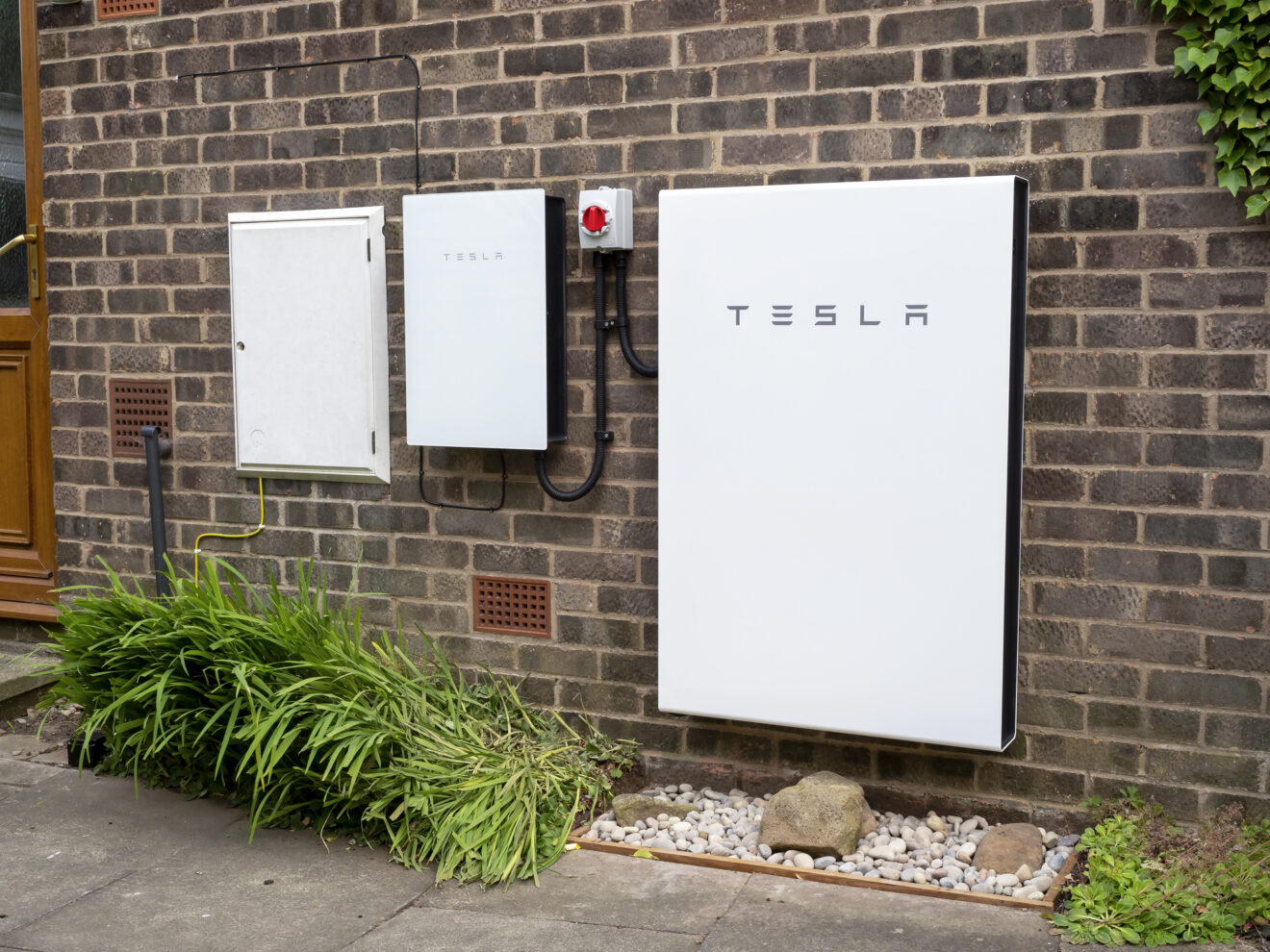 Tesla Powerwall installed on a brick house wall