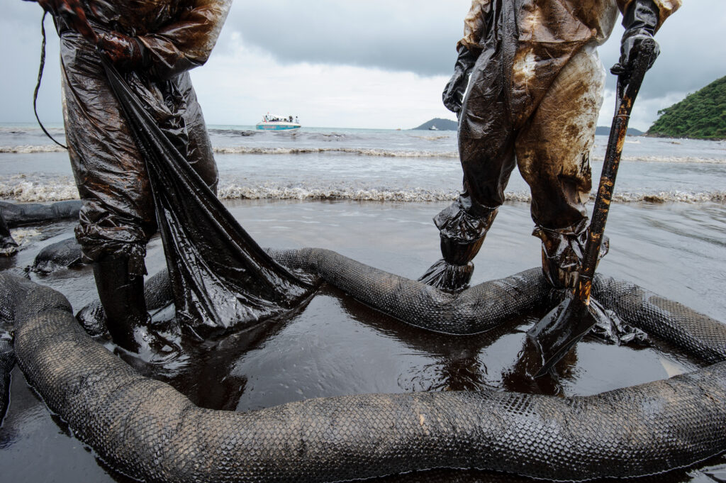 Two men collecting oil on the shore after an oil spill accident on Ao Prao Beach at Samet island on July 31,2013 in Rayong,Thailand