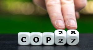 Hand turns cubes and changes the expression 'COP27' to 'COP28'.