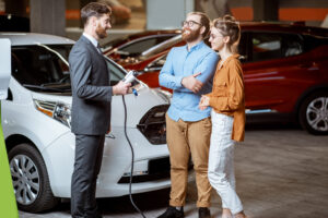 Sales manager showing car charging station to a young couple